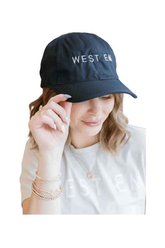 West Em black Nike Dri-Fit hat modeled by Rae – lightweight performance cap with embroidered logo at West Em Medical Spa